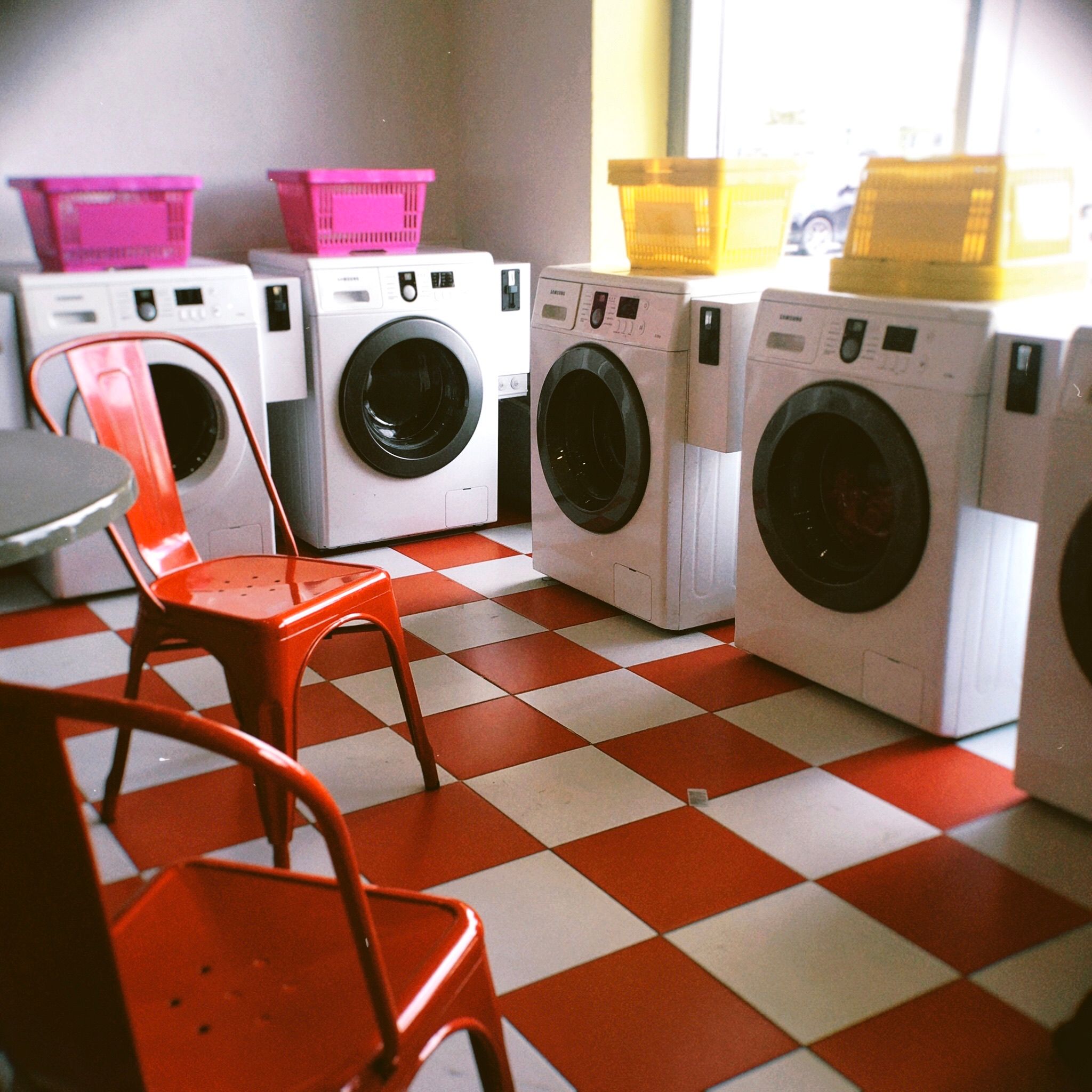 Bright laundry room with red checkered floor and colorful baskets, offering a modern look.